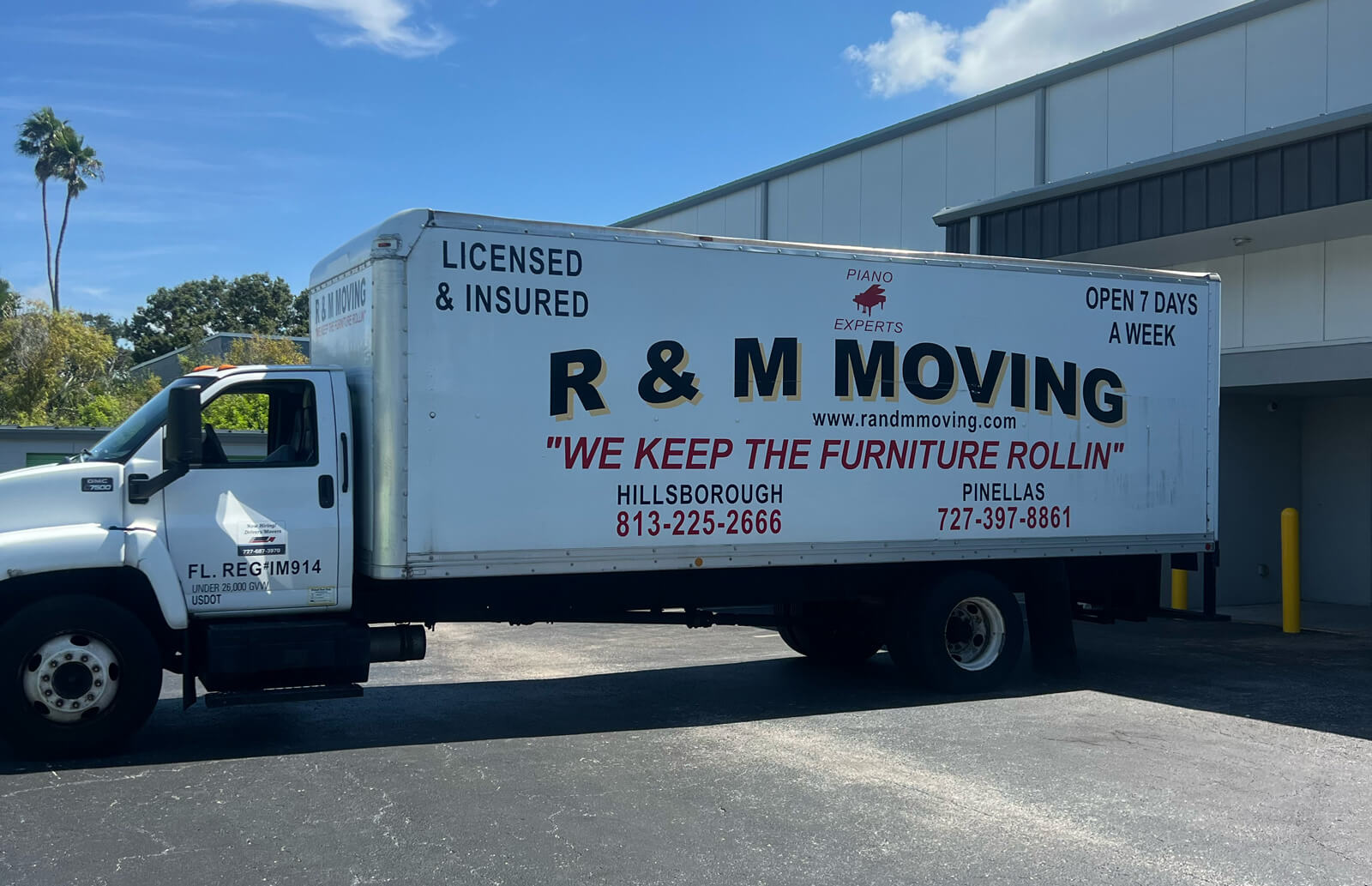 Side profile of an R & M Moving truck parked at a commercial facility highlighting piano moving expertise and licensed insured services.